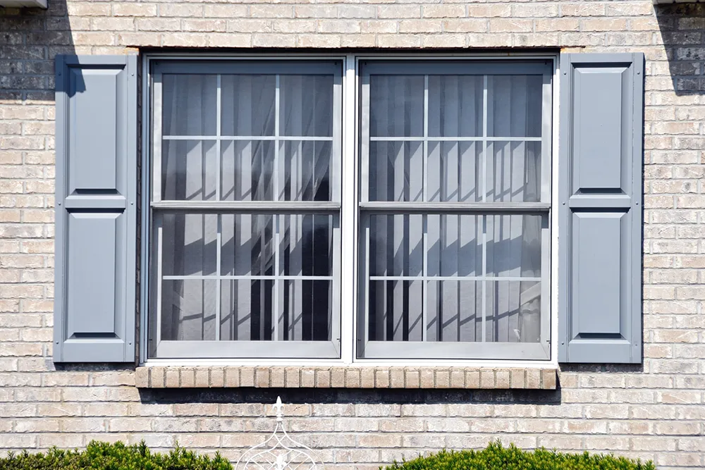 White brick house exterior with double-hung windows and gray shutters