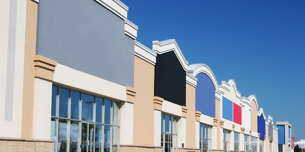 Row of colorful storefronts under a clear blue sky at a shopping center